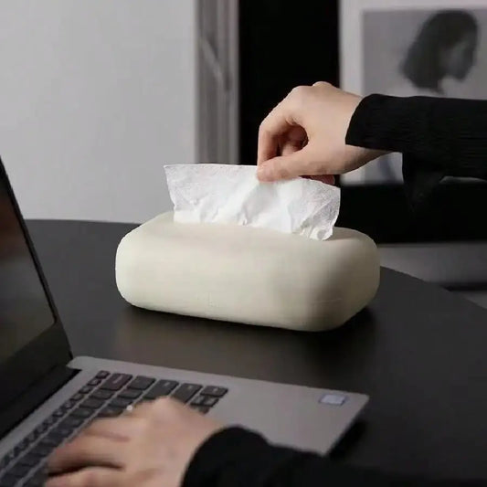 Person using a tissue box on a desk with a laptop