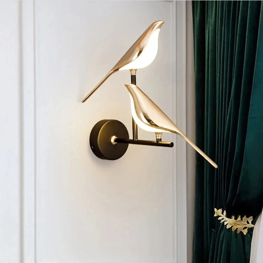Modern wall lamp with gold bird design on a white wall with green curtain.