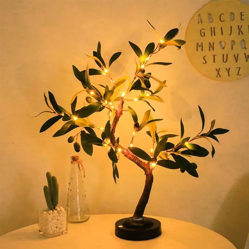 Decorative tree with lights on a table against a plain wall with a letter board.