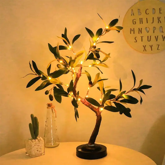 Decorative tree with lights on a table against a plain wall with a letter board.