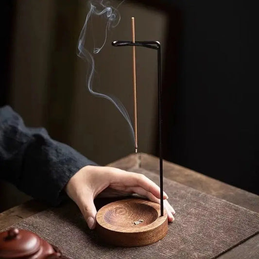 Wooden incense burner with a smoking incense stick on a dark surface