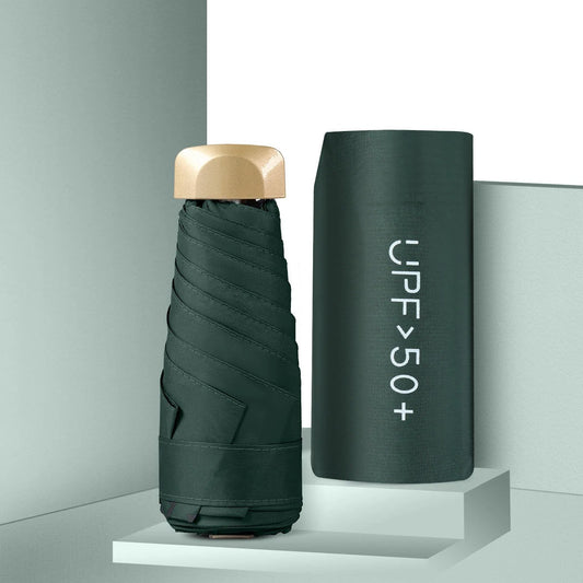 Foldable umbrella with gold cap and cylindrical case labeled 'UPF>50+' on a gray background