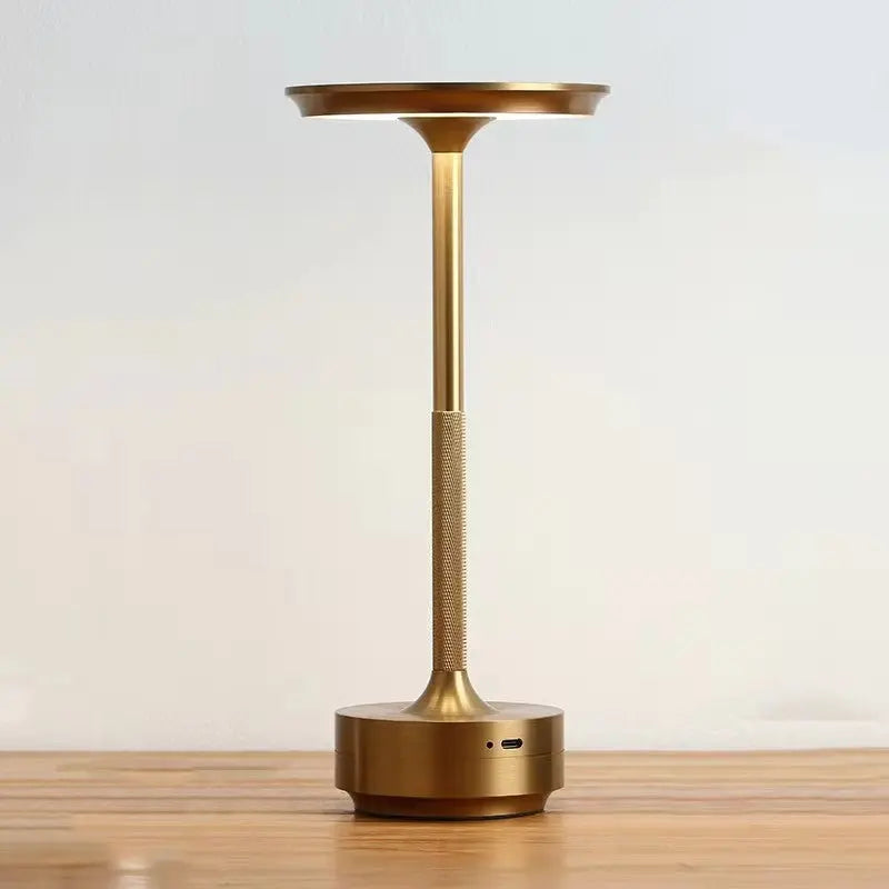 Bronze-colored lamp on a wooden surface with a light background