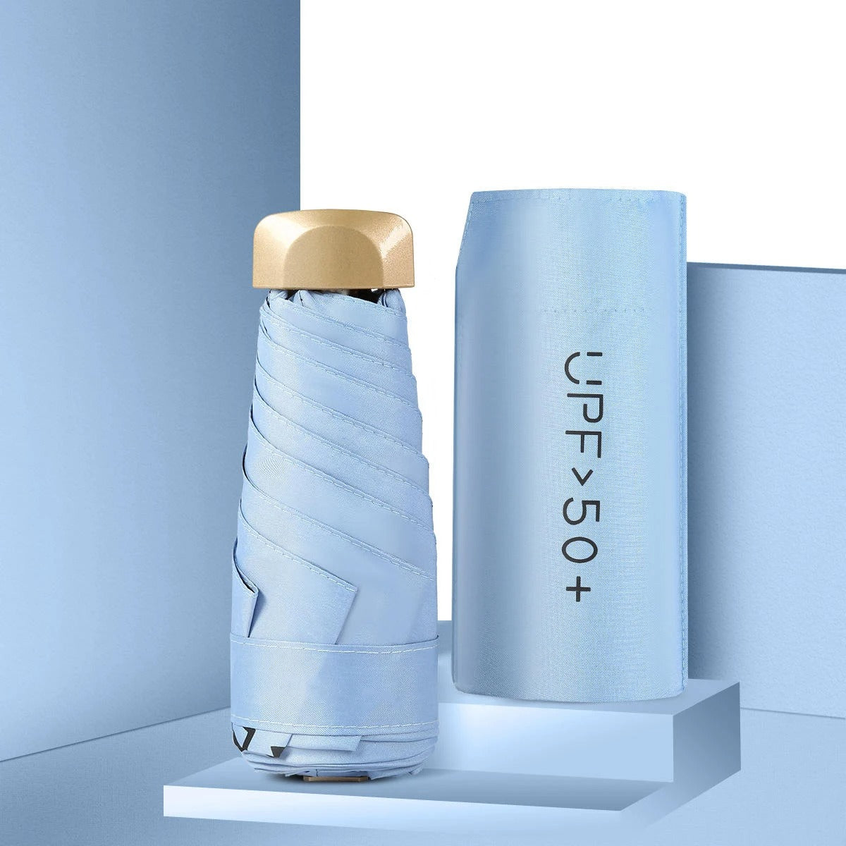 Light blue umbrella with gold top and matching case on a light blue background