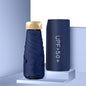 Foldable navy umbrella with gold handle and matching case on a light blue background
