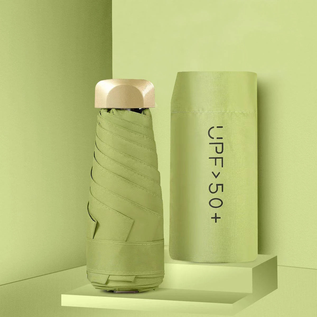 Foldable green umbrella with a matching carrying case on a light green background