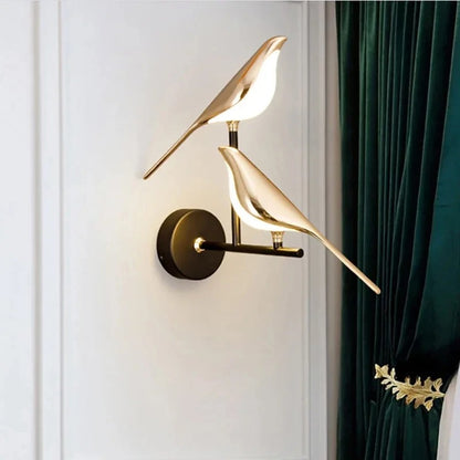 Modern wall lamp with gold bird design on a white wall with green curtain.