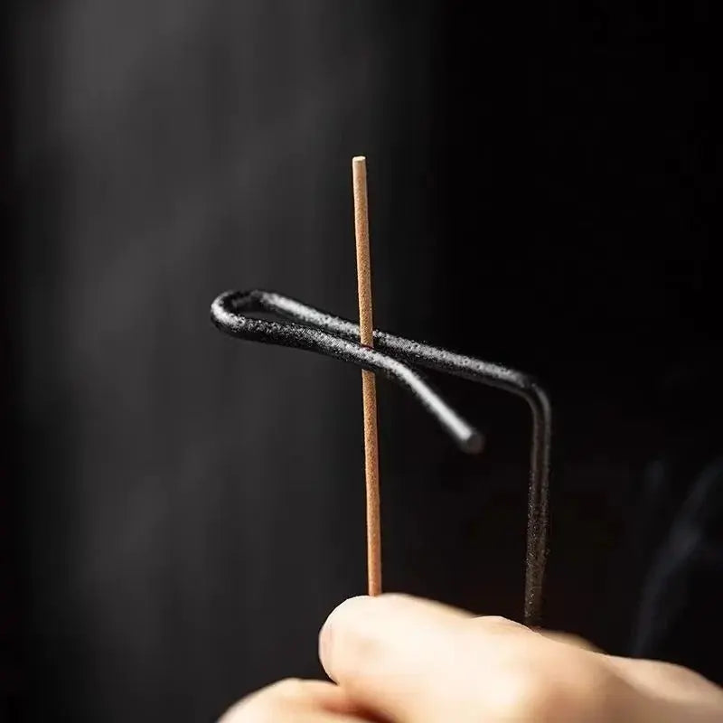 Hand holding a thin metal rod with a black background