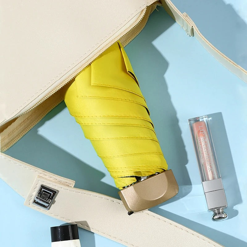 Yellow umbrella and lip gloss in a beige case on a light blue background