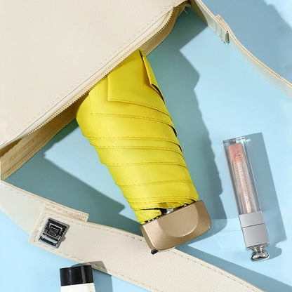 Yellow umbrella and lip gloss in a beige case on a light blue background