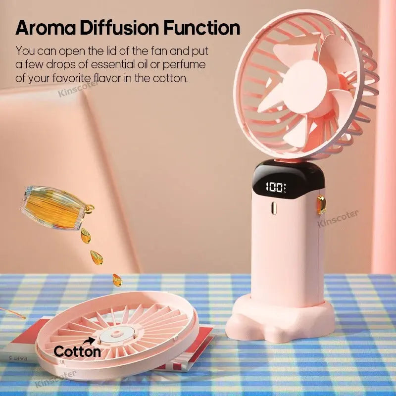 Pink handheld fan with aroma diffusion function on a checkered tablecloth.