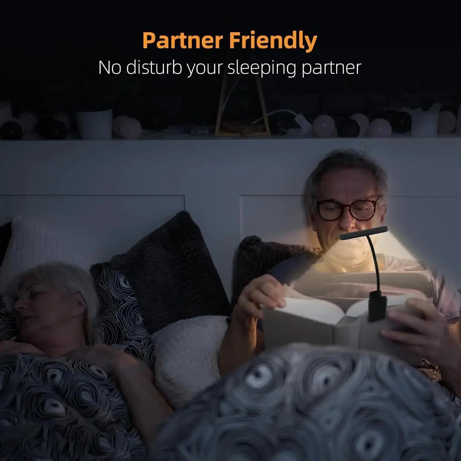 Person reading a book with a lamp near a sleeping partner, emphasizing 'Partner Friendly' feature.