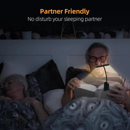 Person reading a book with a lamp near a sleeping partner, emphasizing 'Partner Friendly' feature.