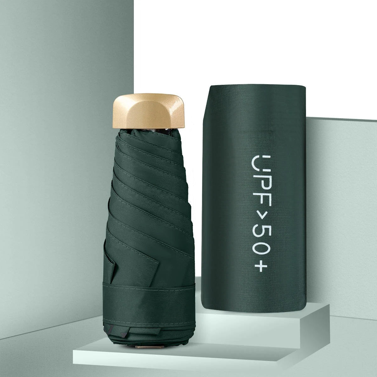 Foldable umbrella with gold cap and cylindrical case labeled 'UPF>50+' on a gray background