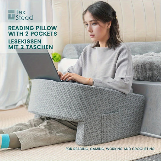 Woman using a laptop on a reading pillow with two pockets, branded 'Tex Stead'.